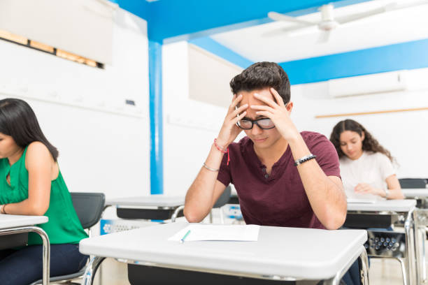teenage pupil worried in test while sitting with classmates in school